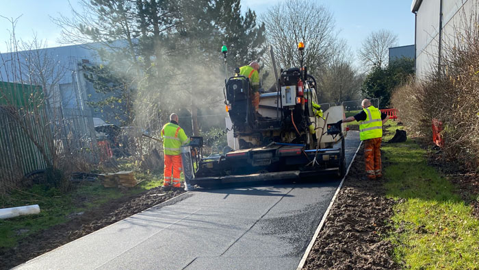 road surfacing being set into place using machinery run by three male workers