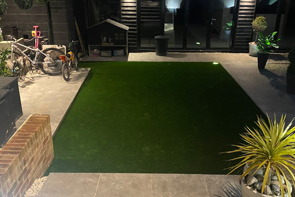 hard landscaping of modern small garden Astroturf surrounded by patio stone slabs